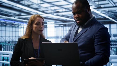 Portrait of young woman using digital tablet while standing in office