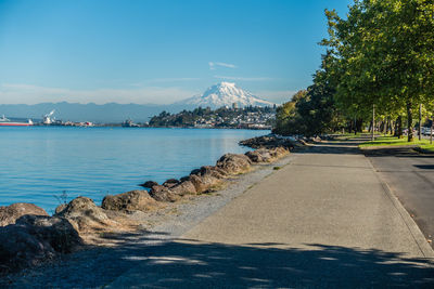 Scenic view of road by sea against blue sky