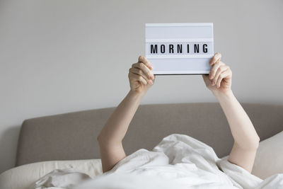 Midsection of woman holding mobile phone while relaxing on bed at home