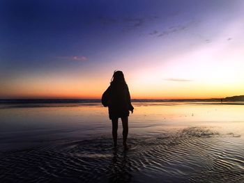 Silhouette woman standing on beach against clear sky