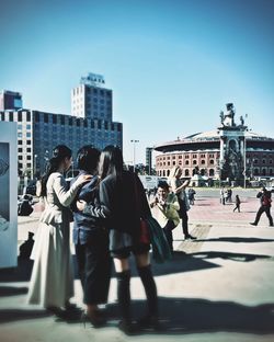 People standing in city against clear sky