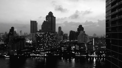 City at waterfront against cloudy sky