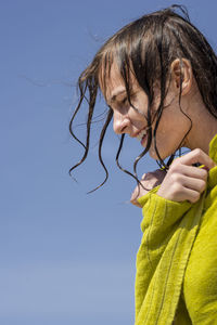 Side view of young woman looking away against clear sky