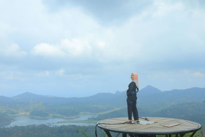 Portrait of smiling woman standing on built structure against sky