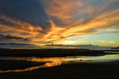 Scenic view of lake against dramatic sky during sunset