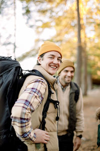 Side view of happy young man with backpack by male friend