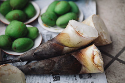 Close-up of unripe mangoes on plates with vegetable 