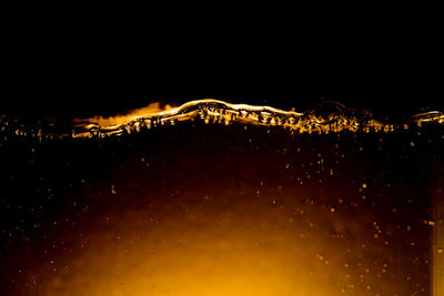 Close-up of water drops on illuminated glass against sky at night