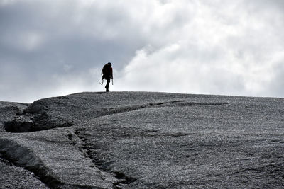 Rear view of person standing on glacier ice against sky