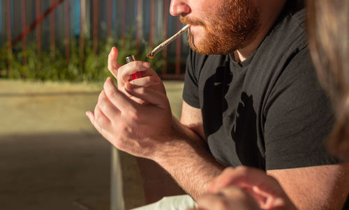 Midsection of man smoking marijuana joint outdoors