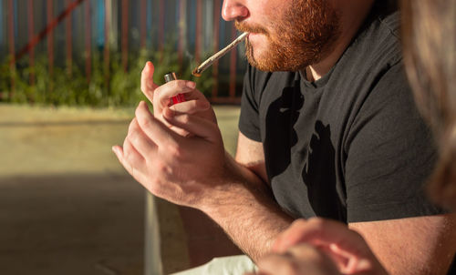 Midsection of man holding cigarette