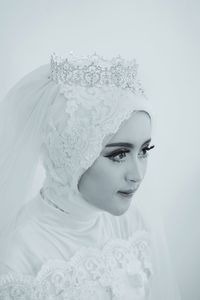 Portrait of young woman with scarf against white background