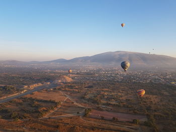 Hot air balloons flying over landscape against sky