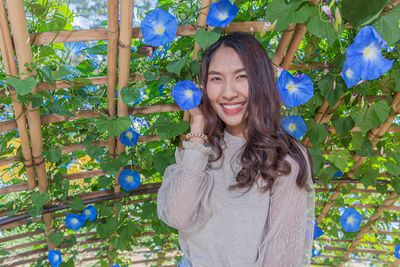 Portrait of smiling young woman standing against plants