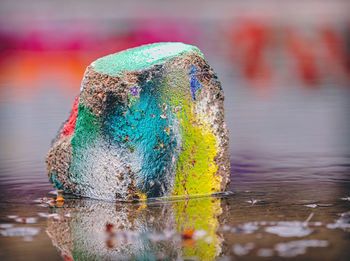 Close-up of multi colored painted rock in puddle 