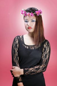 Portrait of young woman standing against red background