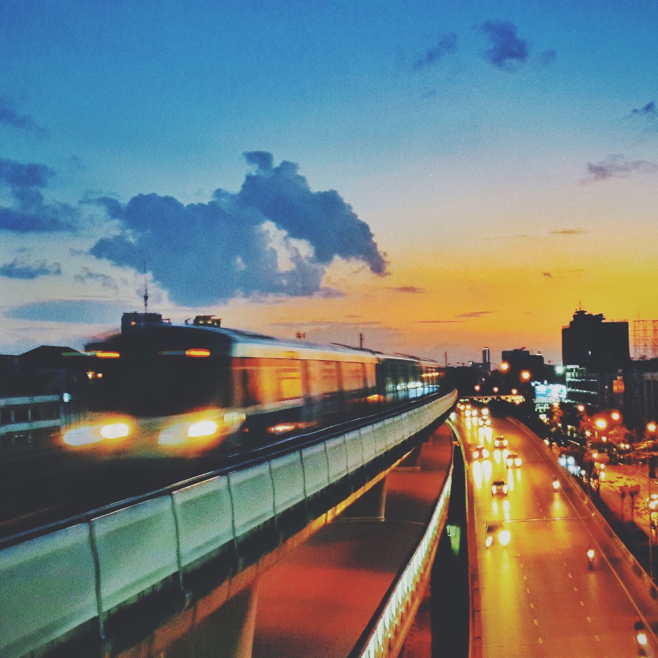 transportation, illuminated, sky, sunset, architecture, built structure, dusk, city, building exterior, road, mode of transport, cloud - sky, railroad track, the way forward, street light, rail transportation, night, land vehicle, public transportation, car