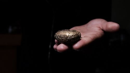 Cropped hand of man holding gold colored religious object