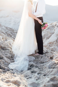 Low section of couple standing on beach