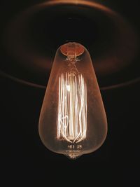 Close-up of illuminated light bulb against black background