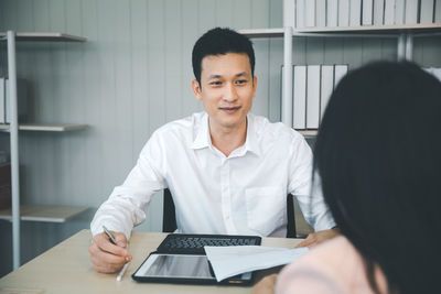 Portrait of a smiling young man sitting on table