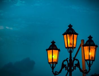 Illuminated street light against sky at night