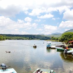 Boats in lake against cloudy sky