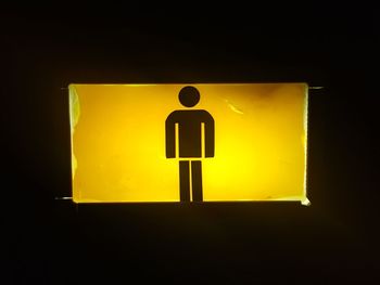 Close-up of yellow sign against black background