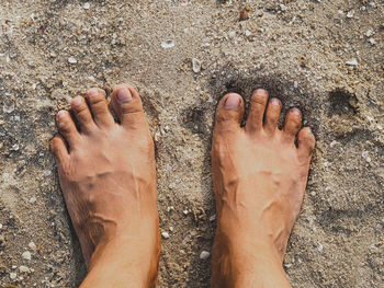 Low section of man standing on sand