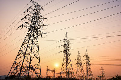 Low angle view of electricity pylon against sky during sunset