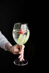 Fresh non-alcoholic cocktail in a female hand on a dark background