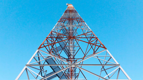 Low angle view of communications tower against clear blue sky