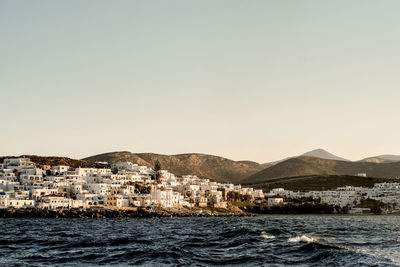 Buildings by sea against clear sky