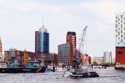 Boats in city by buildings against sky