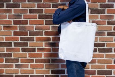 Rear view of person standing against brick wall