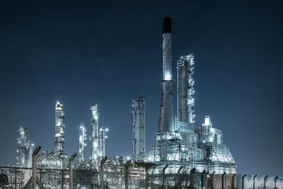 Low angle view of illuminated industry against sky at night