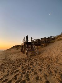 Person on beach against clear sky during sunset