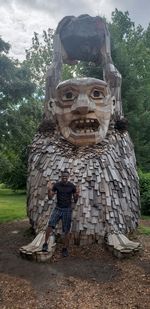 Statue of man standing by sculpture against trees