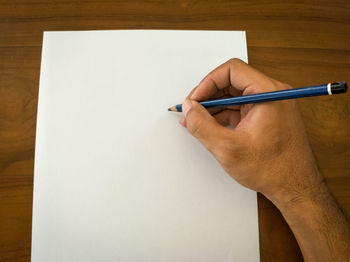 Cropped image of hand holding paper against the wall