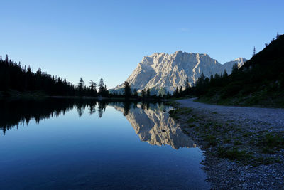 Scenic view of lake and mountains against clear blue sky