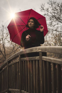 Full length of woman standing on railing during rainy day