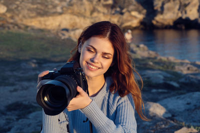 Portrait of smiling young woman with camera