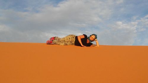 Low angle view of young man sitting against sky