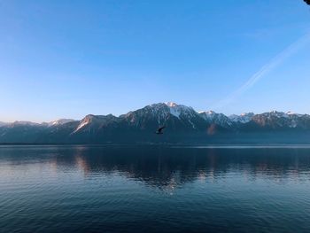 Scenic view of lake and mountains against clear blue sky