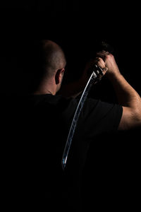 Close-up portrait of man holding cigarette against black background