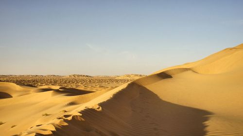 Sand dunes in desert against sky