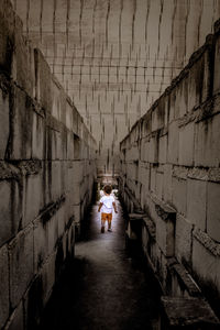 Rear view of people walking on footpath amidst buildings