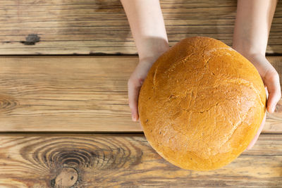 Cropped hand of person holding bread on table