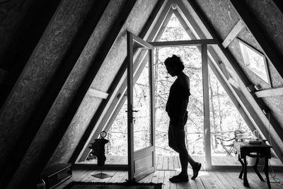 Silhouette portrait of young woman standing in front of door