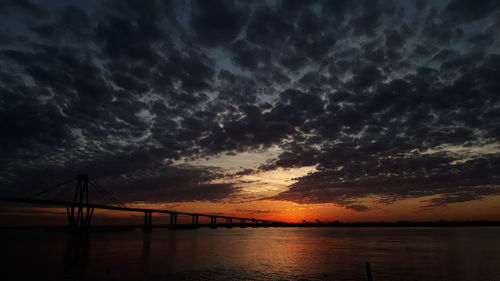 Silhouette bridge over sea against sky during sunset. costanera corrientes capital argentina